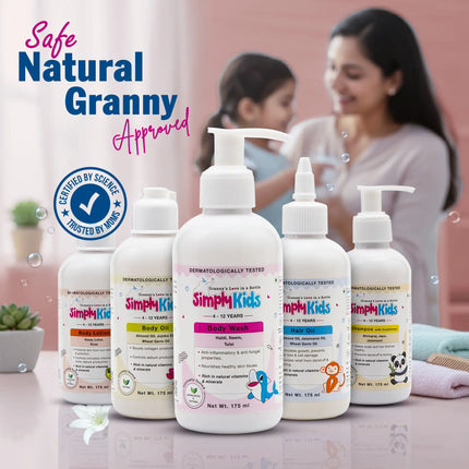 Simply Kids baby care products set including body wash, body oil, body lotion, shampoo and hair oil placed on a table, with a smiling mother and child softly blurred in the background